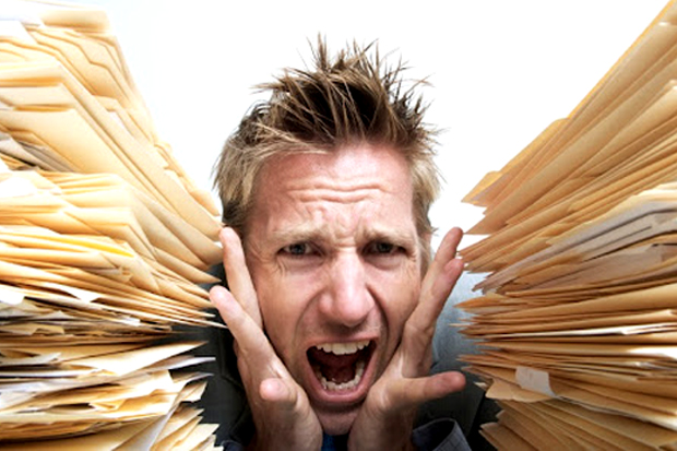 Man with stacks of paper - stress and burnout